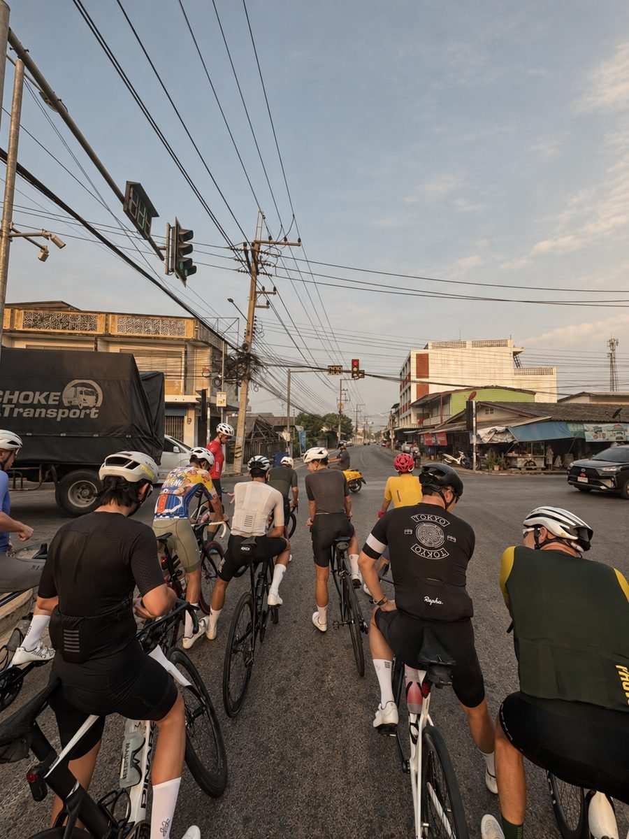 A group of road cyclists waiting at a traffic light at sunrise